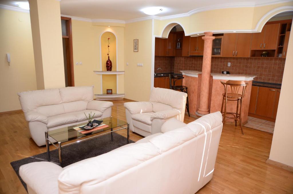 uma sala de estar com sofás brancos e uma cozinha em Exclusive Central Apartments em Skopje