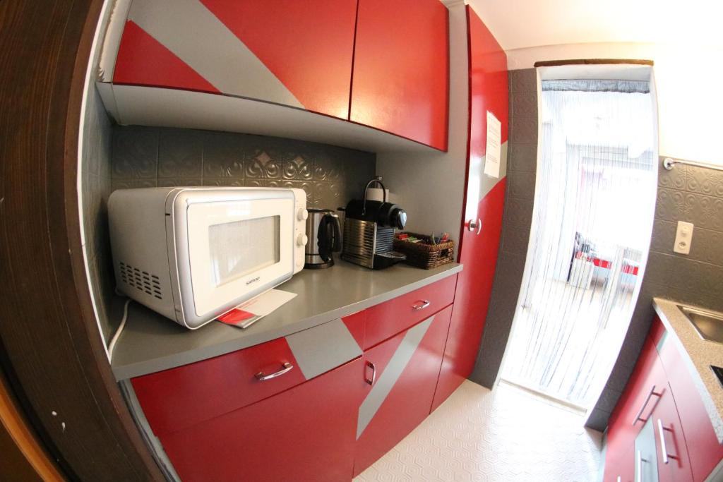 a small kitchen with red cabinets and a microwave at La Ferme des Fées in Bévilard