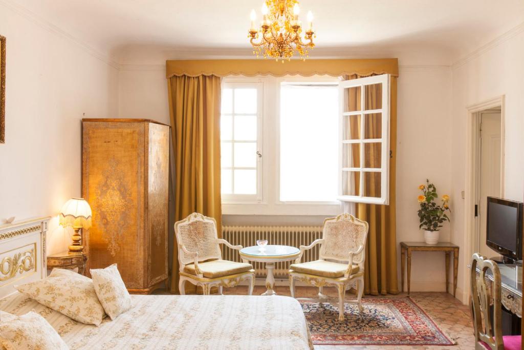 a bedroom with a bed and a table and chairs at Domaine du Paradis des Oiseaux in Mougins