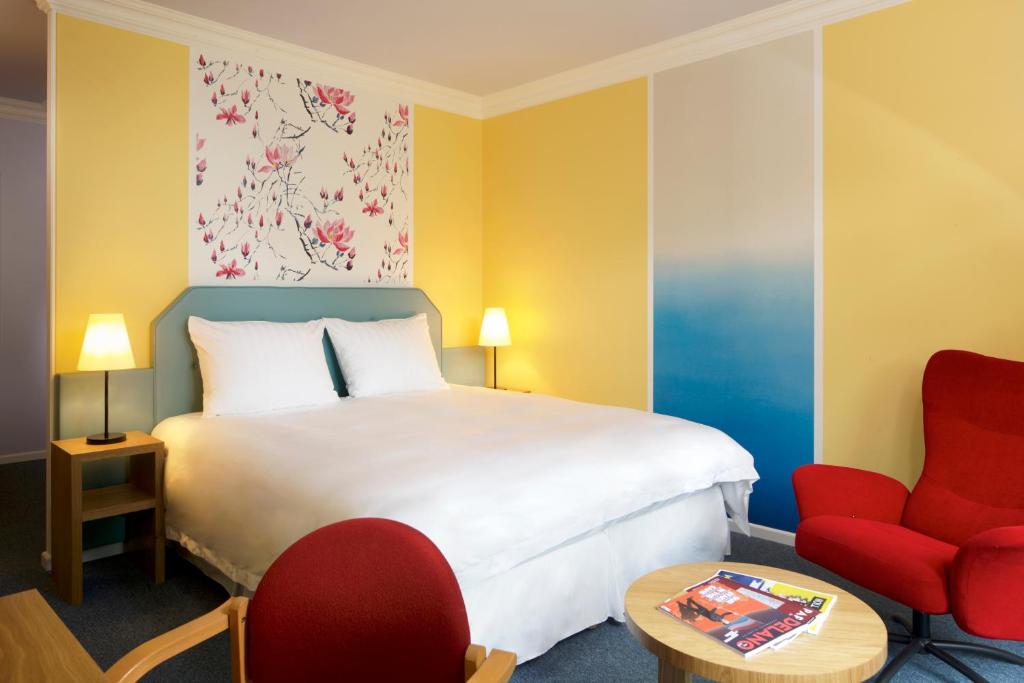 a hotel room with a bed and a red chair at Hotel Parc Plaza in Luxembourg