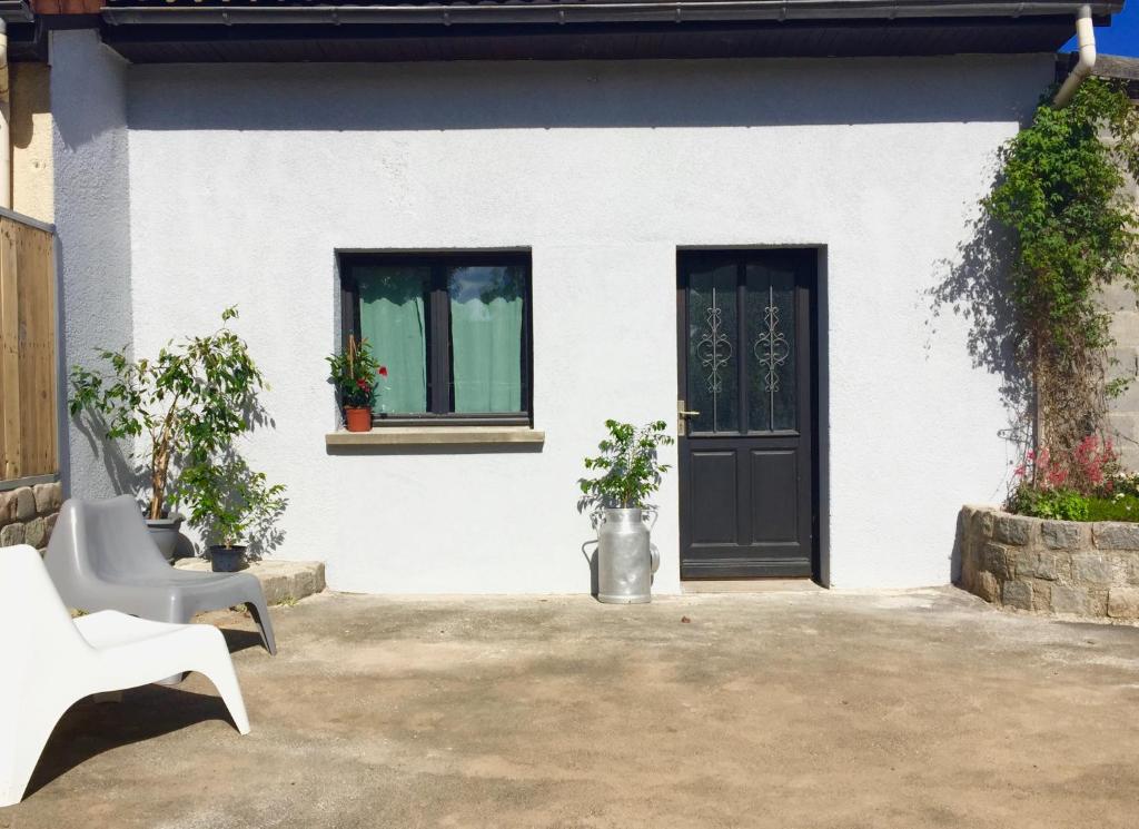 una casa blanca con una puerta negra y dos ventanas en Coeur des Domes, en Fontfreide