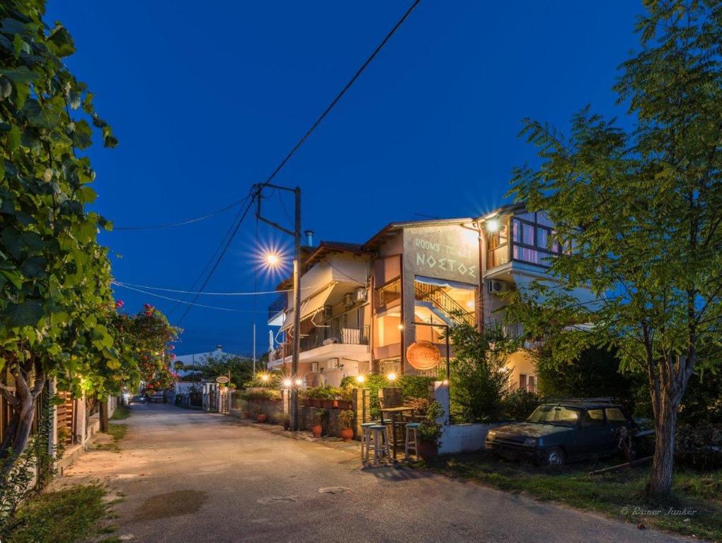 a building with a car parked next to a street at Nostos Apartments in Nea Mesangala