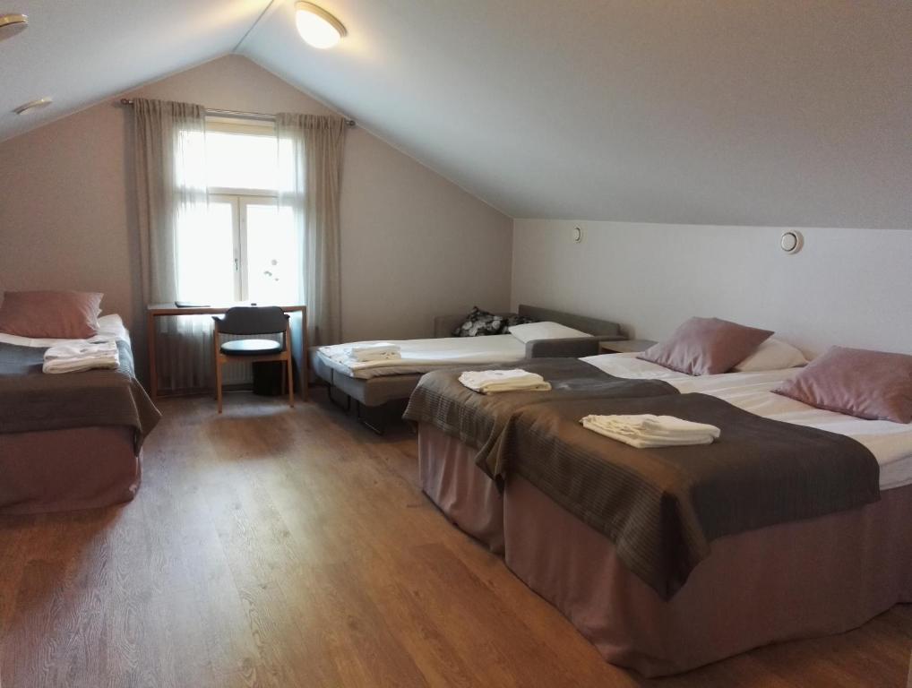a hotel room with three beds and a window at Savonlinnan Kansanopisto - Wanha Pappila in Savonlinna