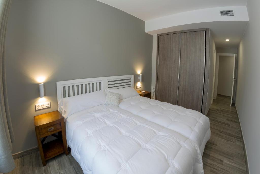 a large white bed in a bedroom with two lamps at Hotel Asador O Callejón De Belchite in Ayerbe