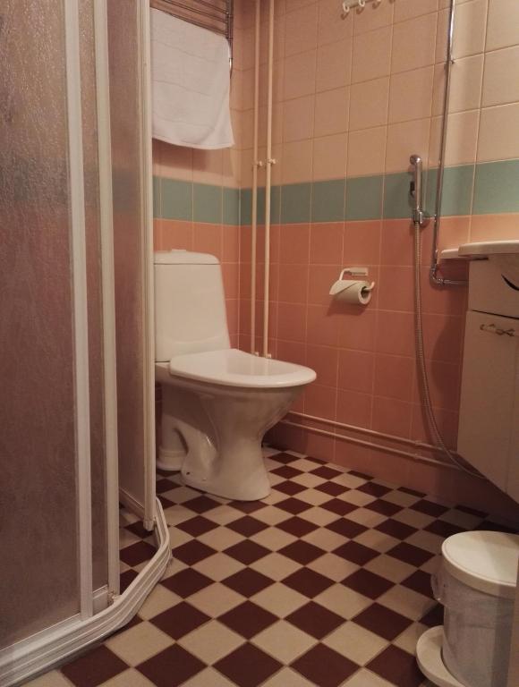 a bathroom with a toilet and a shower with a checkered floor at Savonlinnan Kansanopisto - Wanha Pappila in Savonlinna