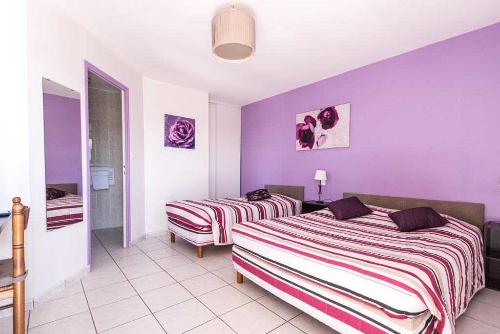 duas camas num quarto com paredes roxas em Le Grand Jardin em Aujargues