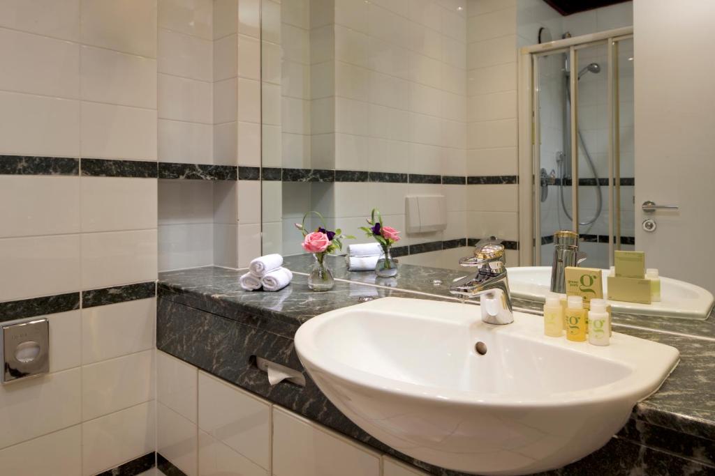 a bathroom with a white sink and a mirror at Hotel Parc Belair in Luxembourg