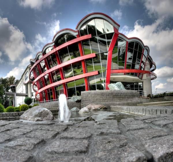 un gran edificio rojo con una fuente frente a él en Hotel Olympic, en Wronki