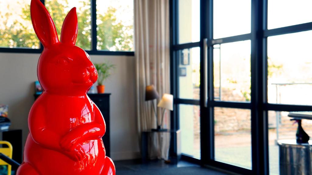 a red statue of a rabbit sitting in front of a window at Hotel-Restaurant Lann Roz / Côte Cuisine in Carnac