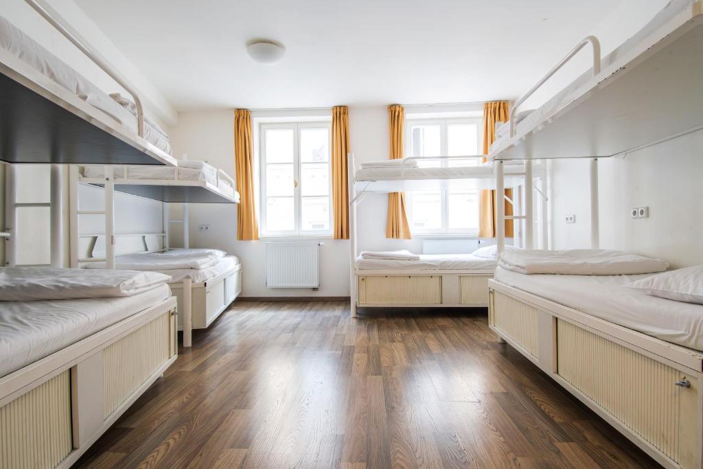 a room with three bunk beds and wooden floors at Safestay Prague Charles Bridge in Prague
