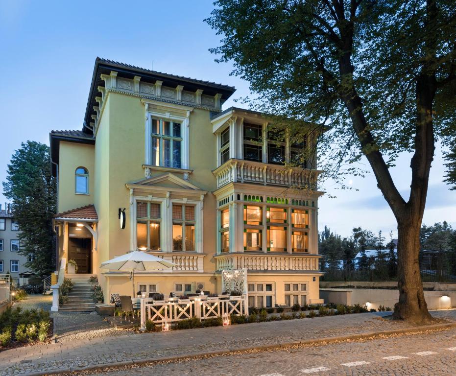 una grande casa gialla con un albero di fronte di Hotel Impresja a Danzica