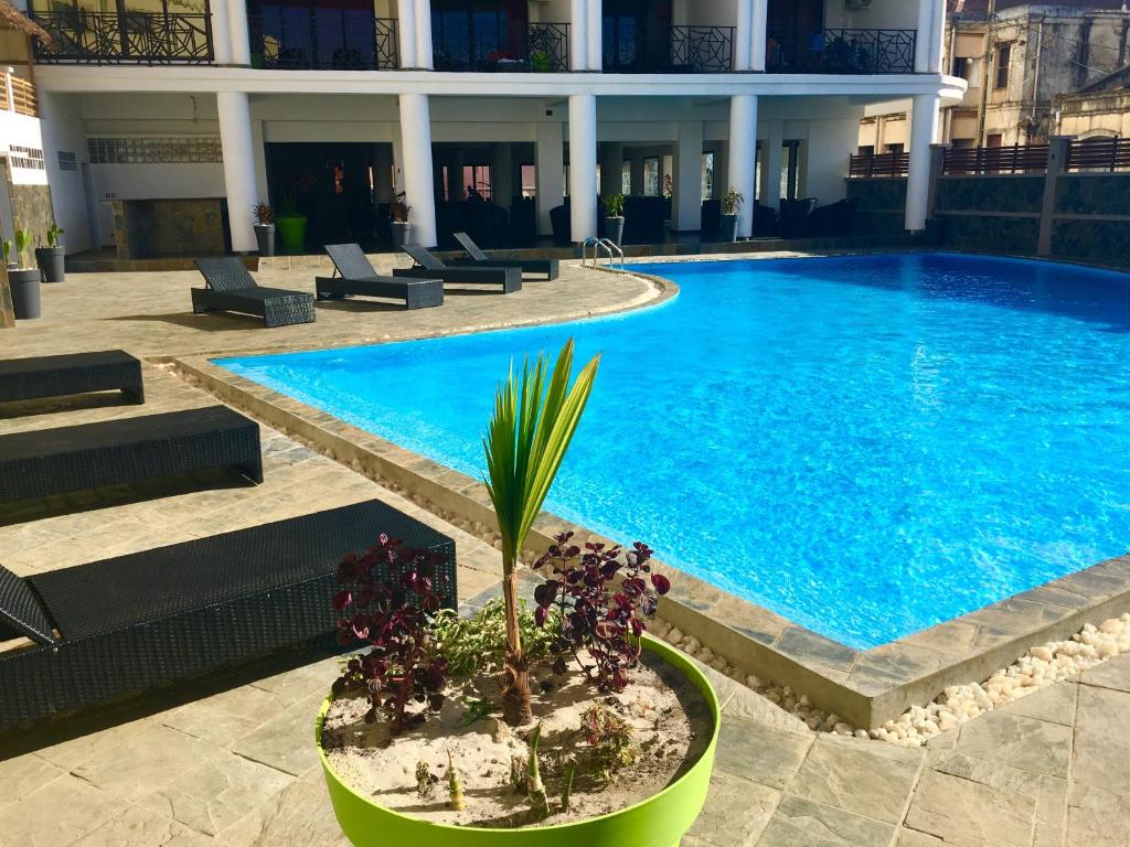 a large swimming pool with a potted plant next to it at Hotel de la Poste in Antsiranana