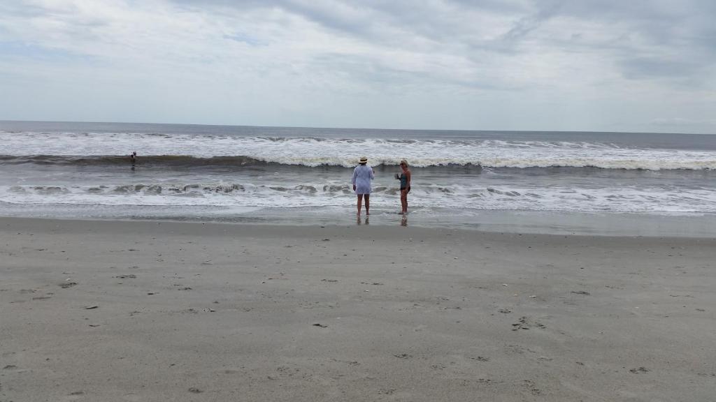 twee mensen op het strand die naar de oceaan kijken bij Holden Beach Your Way in Holden Beach