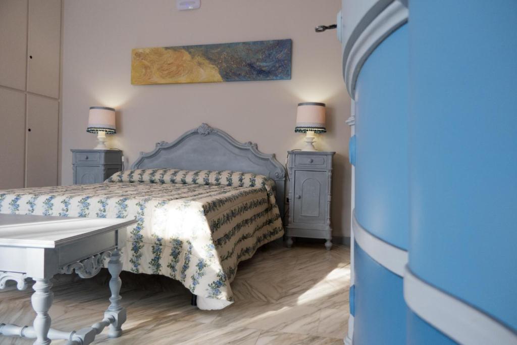 sypialnia z łóżkiem ze stołem i 2 stolikami nocnymi w obiekcie Yucca Camere & Suite w mieście Trani