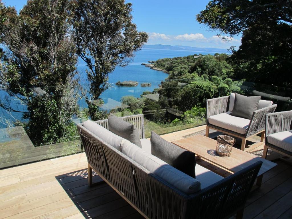 um pátio com uma mesa e cadeiras e vista para a água em The Point Luxury Villa em Taupo