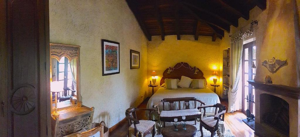 ein Schlafzimmer mit einem Bett und Stühlen in einem Zimmer in der Unterkunft Cissus Hotel Boutique in Antigua Guatemala