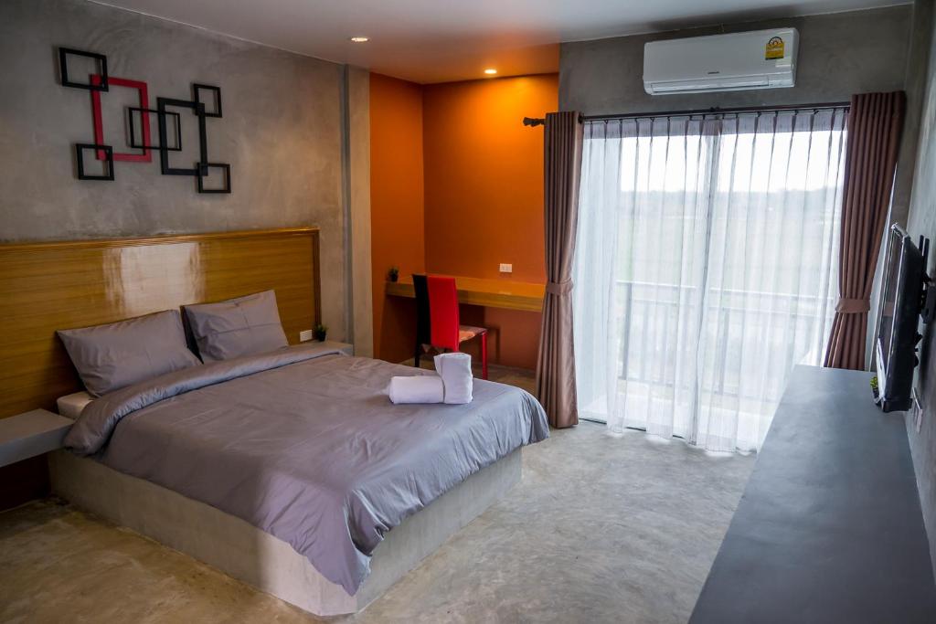 Schlafzimmer mit einem Bett, einem Schreibtisch und einem Fenster in der Unterkunft B3 Hotel in Nakhon Si Thammarat