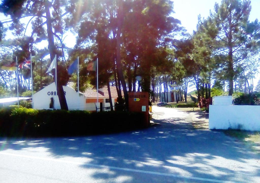 un bâtiment avec un panneau à côté des arbres dans l'établissement Parque de Campismo Orbitur Sao Jacinto, à São Jacinto