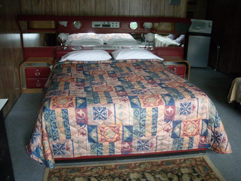a bedroom with a bed with a quilt on it at Motel le Verseau in Sorel