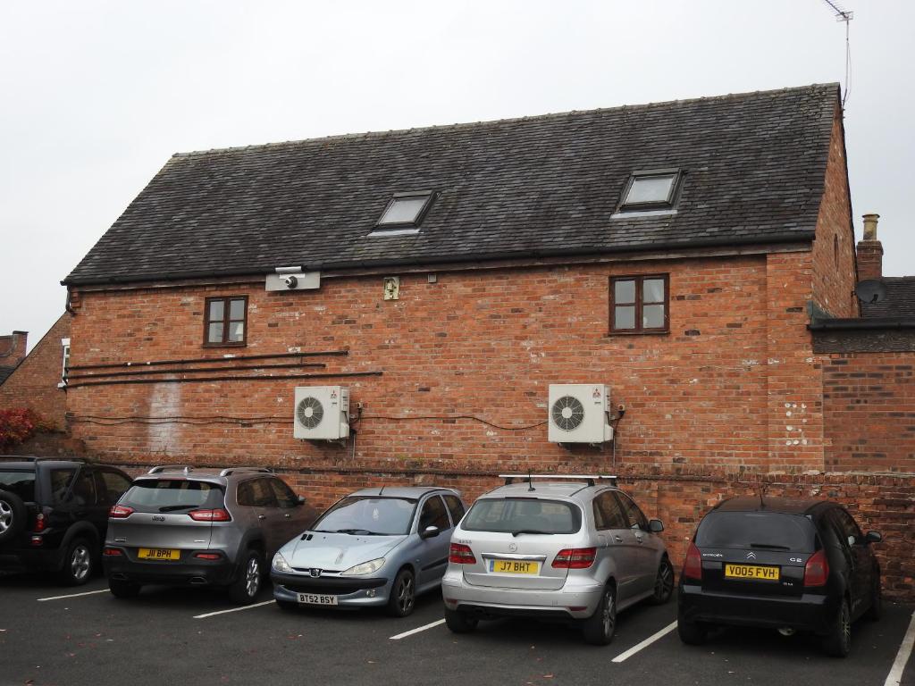 um grupo de carros estacionados em frente a um edifício de tijolos em Pillory House Loft Apartment em Nantwich