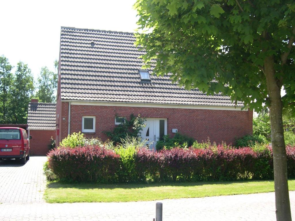 a red brick house with a red van in front of it at Ferienhaus Klabautermann in Hage