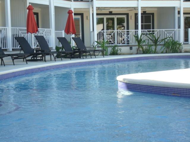 a swimming pool with chairs and umbrellas in a hotel at Lantana Resort Barbados by Island Villas in Saint James