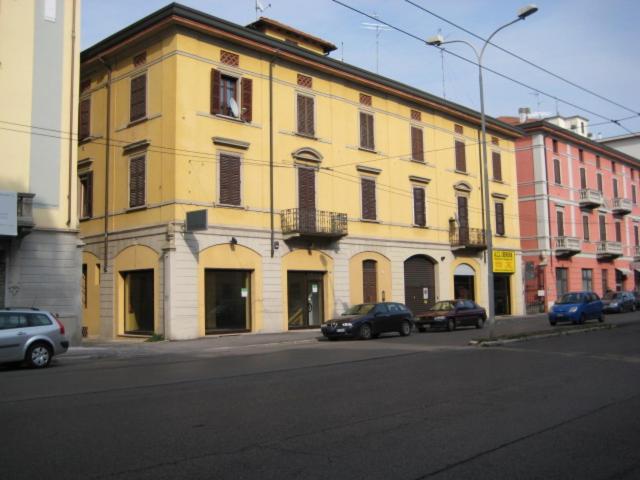 ein großes gelbes Gebäude mit Autos auf einer Straße in der Unterkunft Altana Piccionaia di Via Dante in Cremona
