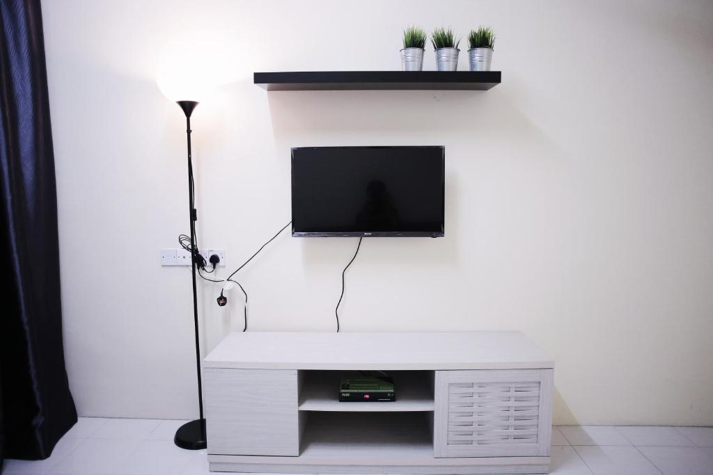 een woonkamer met een tv aan een witte muur bij Arau Idaman Homestay in Arau