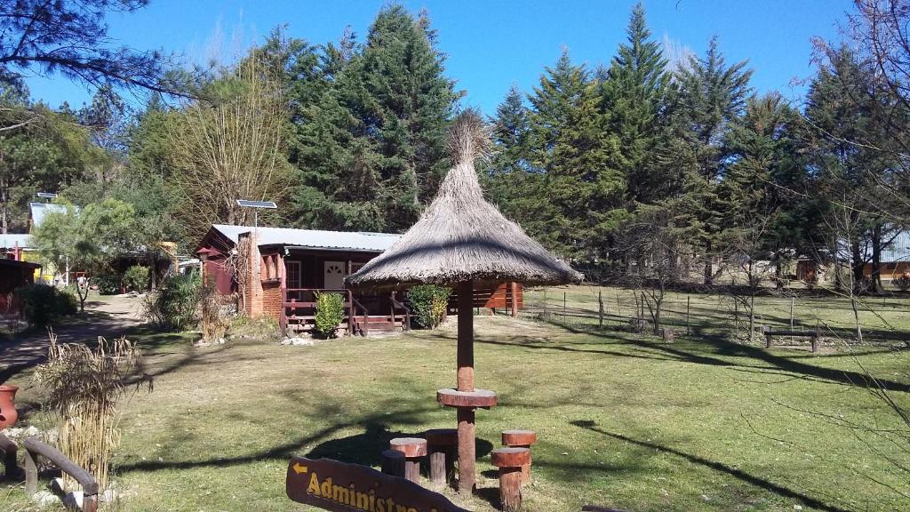 un gran paraguas de paja en medio de un patio en Cabañas "La Quimera" en El Durazno