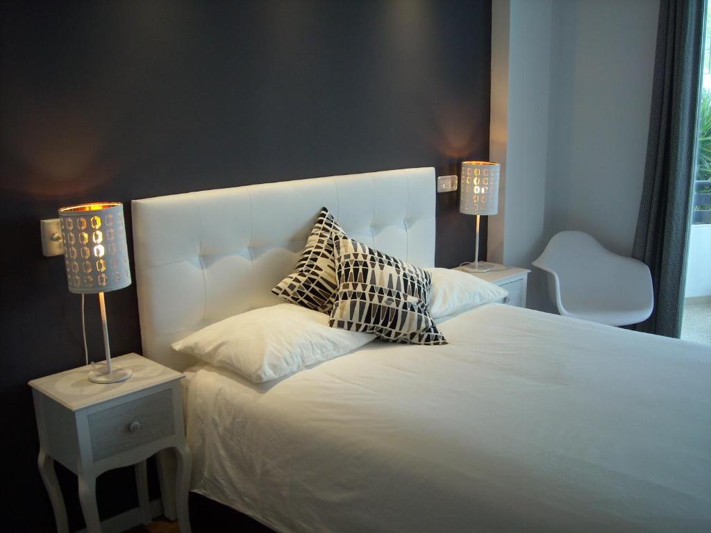 イリェタスにあるEstudios Bahiaのベッドルーム1室(白いベッド1台、枕、ランプ2つ付)