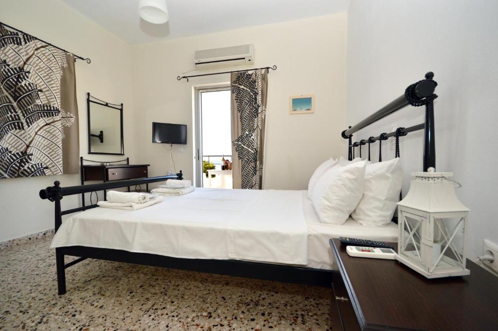 a bedroom with a large bed and a desk with a lamp at Koukounari 2 Rooms in Skala