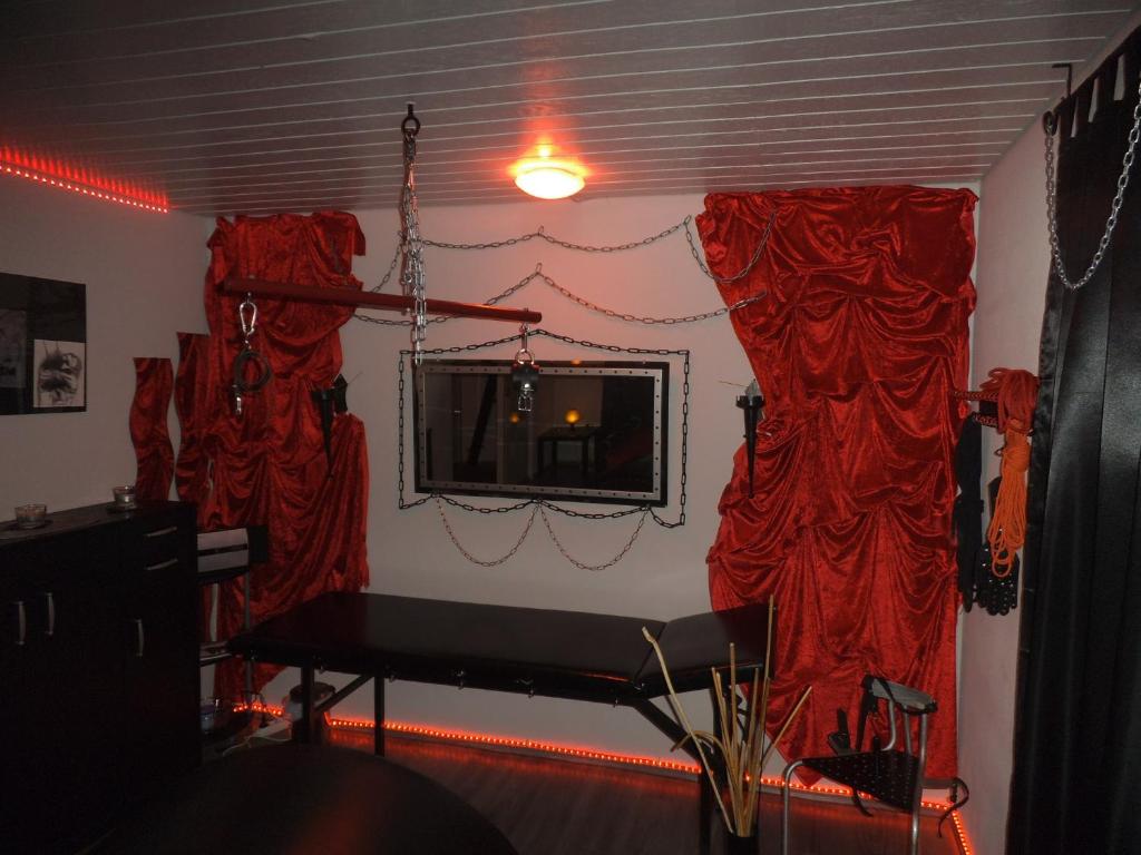 a room with red curtains and a table and a mirror at Exclusiv-Mietapartment (BDSM)-Heidelberg in Heidelberg