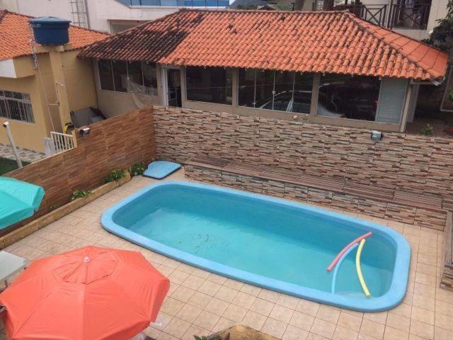 una gran piscina con una sombrilla roja y una casa en Pousada Altos dos Ingleses, en Florianópolis