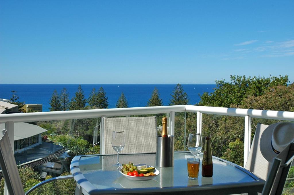 una mesa con dos copas de vino y un tazón de comida en Sunshine Vista, en Sunshine Beach