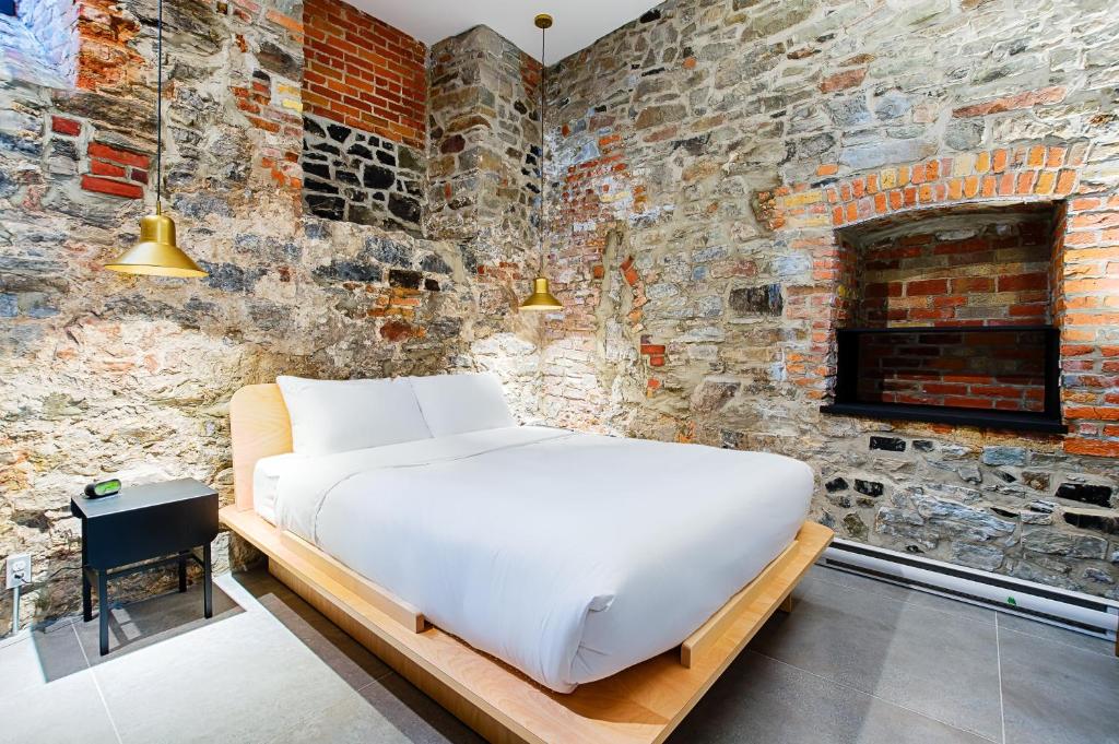 a bed in a room with a brick wall at Les Lofts Notre-Dame - Par Les Lofts Vieux-Québec in Quebec City