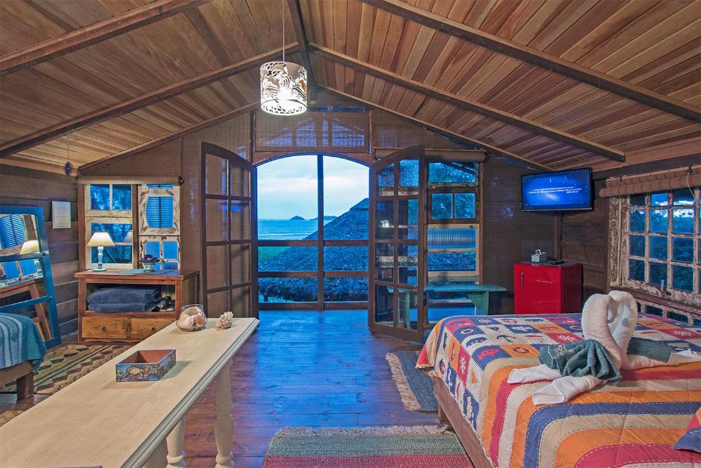 een slaapkamer met een bed en een groot raam bij Hotel Pousada Praia do Farol in Ilha do Mel