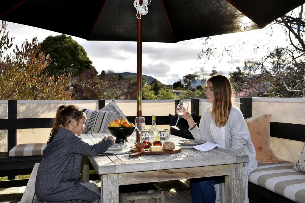 zwei Frauen, die an einem Tisch unter einem Schirm sitzen in der Unterkunft Tongariro Adventures in Kuratau