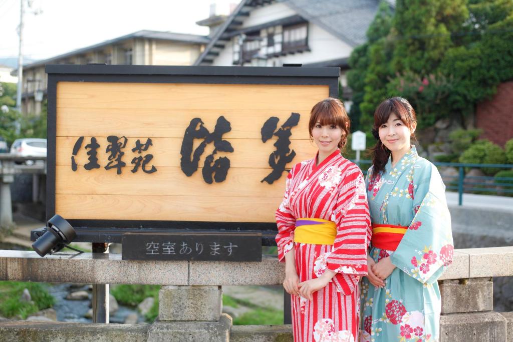 duas mulheres de quimonos em frente a um cartaz em Kasuien Minami em Matsue