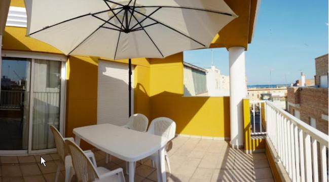 a white table and chairs on a balcony with an umbrella at Mediterrania Pinazo in Puerto de Sagunto