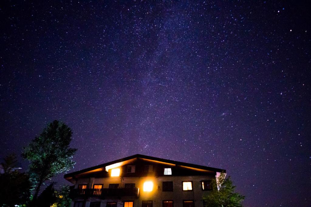een gebouw 's nachts met een sterrenhemel bij Hotel Hakuba Berghaus in Otari