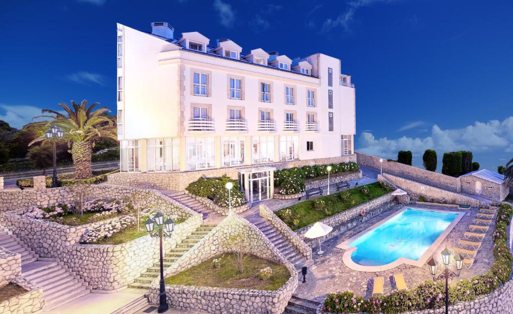 a large white building with a swimming pool in front of it at Hotel Suances in Suances