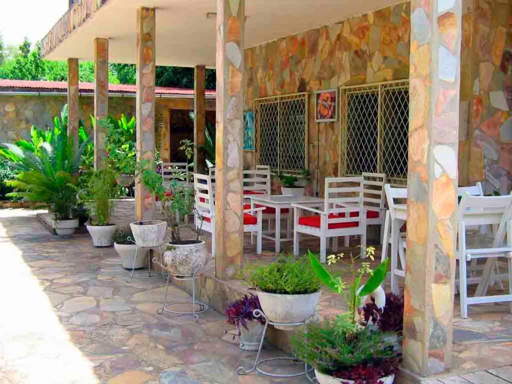 patio z białymi krzesłami, stołami i doniczkami w obiekcie Hotel Chez Fanny w mieście Kpalimé