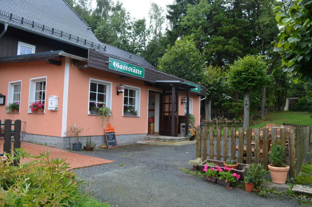 un edificio rosa con una valla delante en Restaurant & Pension Forsthaus Hain en Kurort Oybin