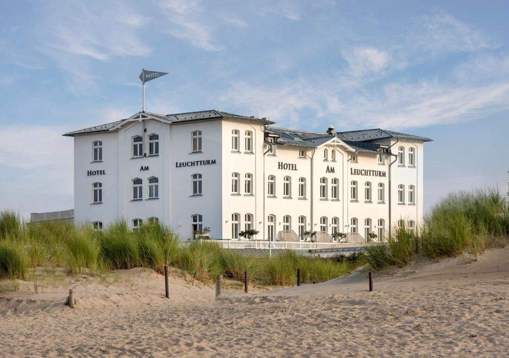 ein großes weißes Gebäude auf einem Strand in der Unterkunft Hotel Am Leuchtturm in Warnemünde