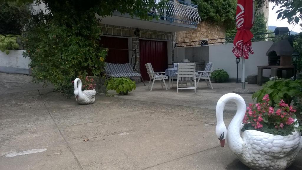 two swans are standing on a patio with flowers at Kuća Rose in Ledenice