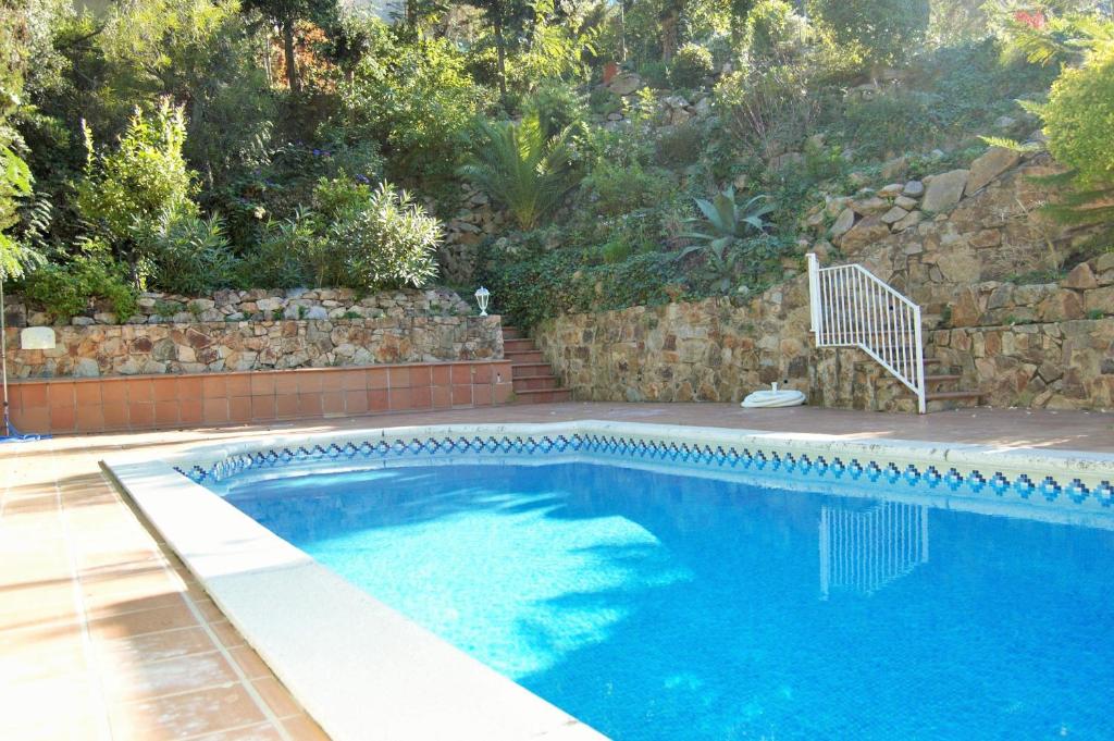 a swimming pool with blue water and a stone wall at Villa Martina in Tossa de Mar