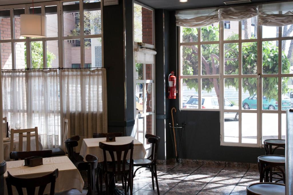 アルアマ・デ・ムルシアにあるHotel Los Bartolosのテーブルと椅子、大きな窓のあるレストラン