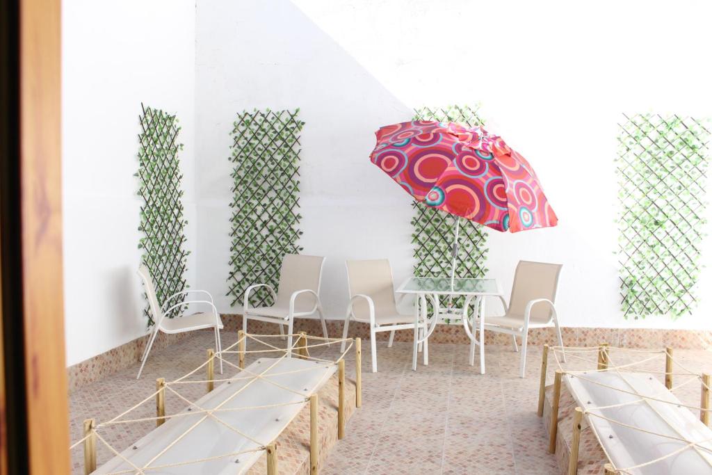 Apartamento de Silvia في أليكانتي: غرفة مع طاولة وكراسي ومظلة حمراء