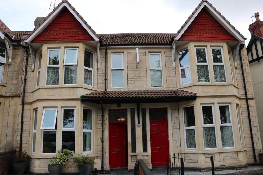 a large house with red doors and windows at Norfolk Guest House in Bristol