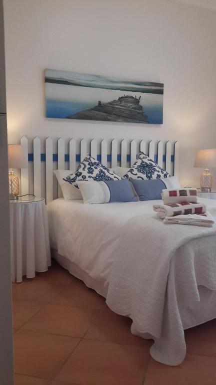 a bedroom with a white bed with blue and white pillows at Summer Place in Vila Praia Do Bilene